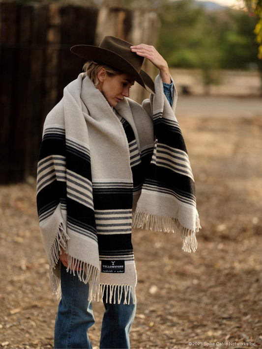 Person wearing a cowboy hat and striped poncho with a visible brand logo.