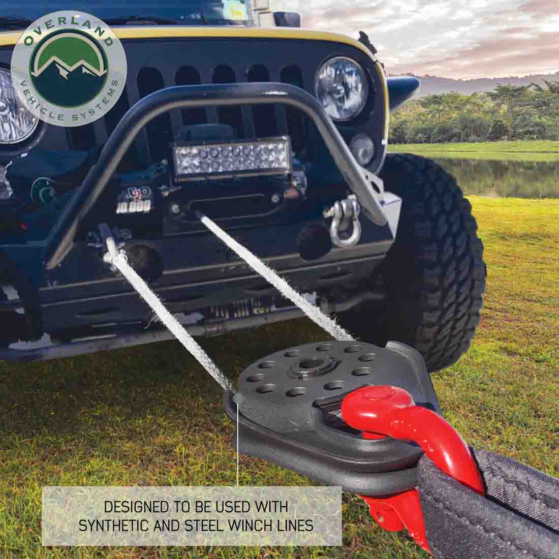 Jeep with a winch attached, featuring Overland Vehicle Systems logo, on a grassy field.