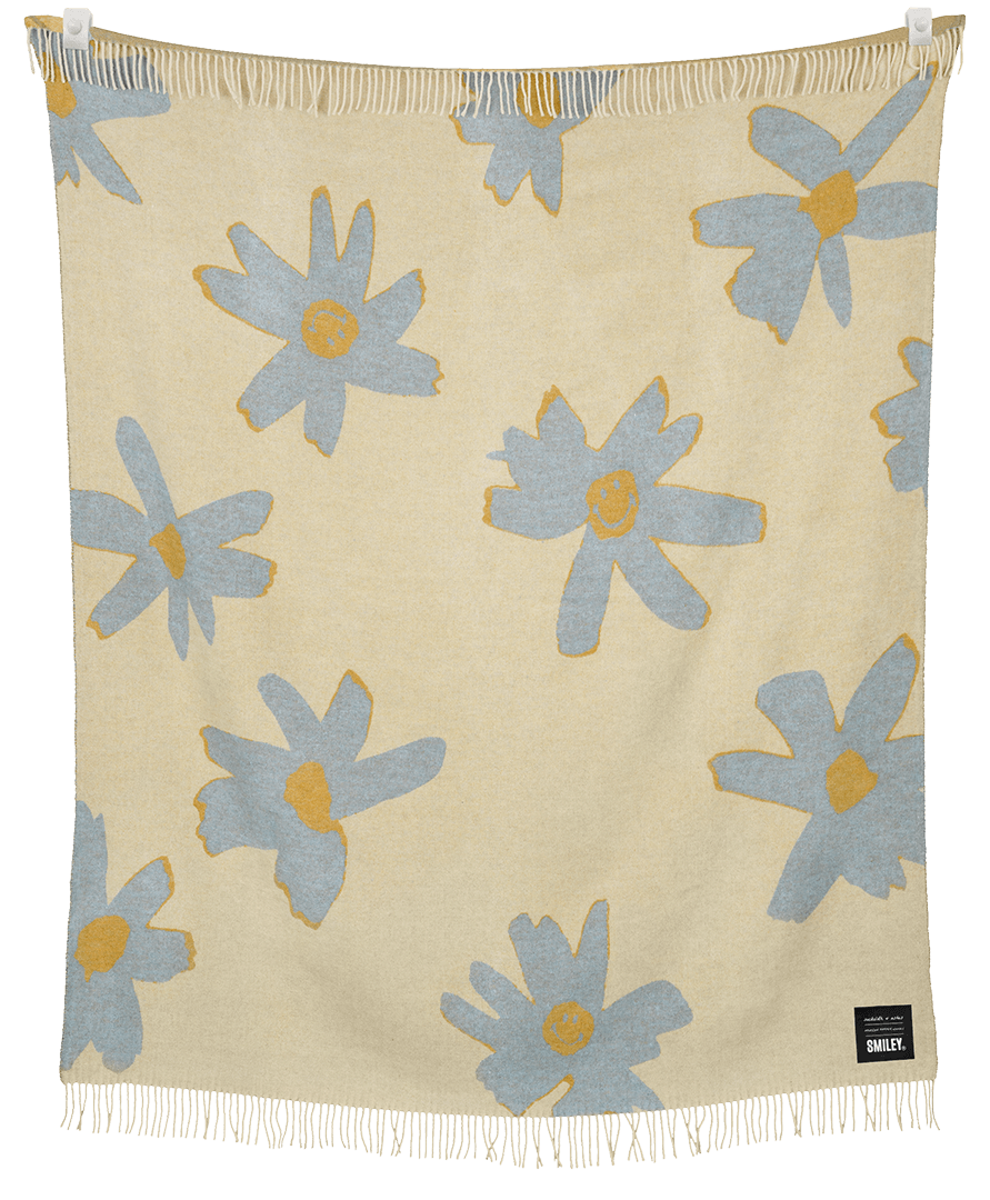 Beige blanket with blue floral patterns and white fringe on a black background