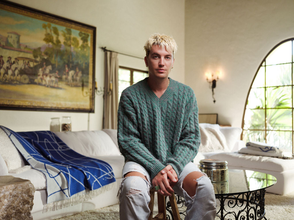 Man sitting on a couch in a living room with a painting and window in the background