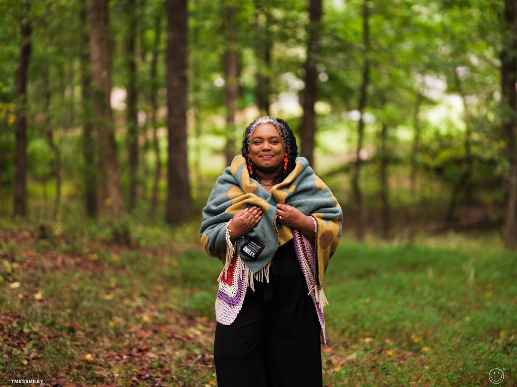 Woman wrapped in a colorful blanket standing in a forest