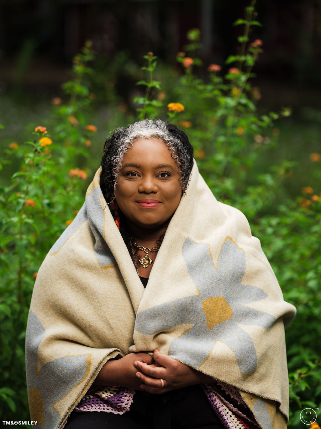 Woman wrapped in a blanket with a floral pattern in a natural setting