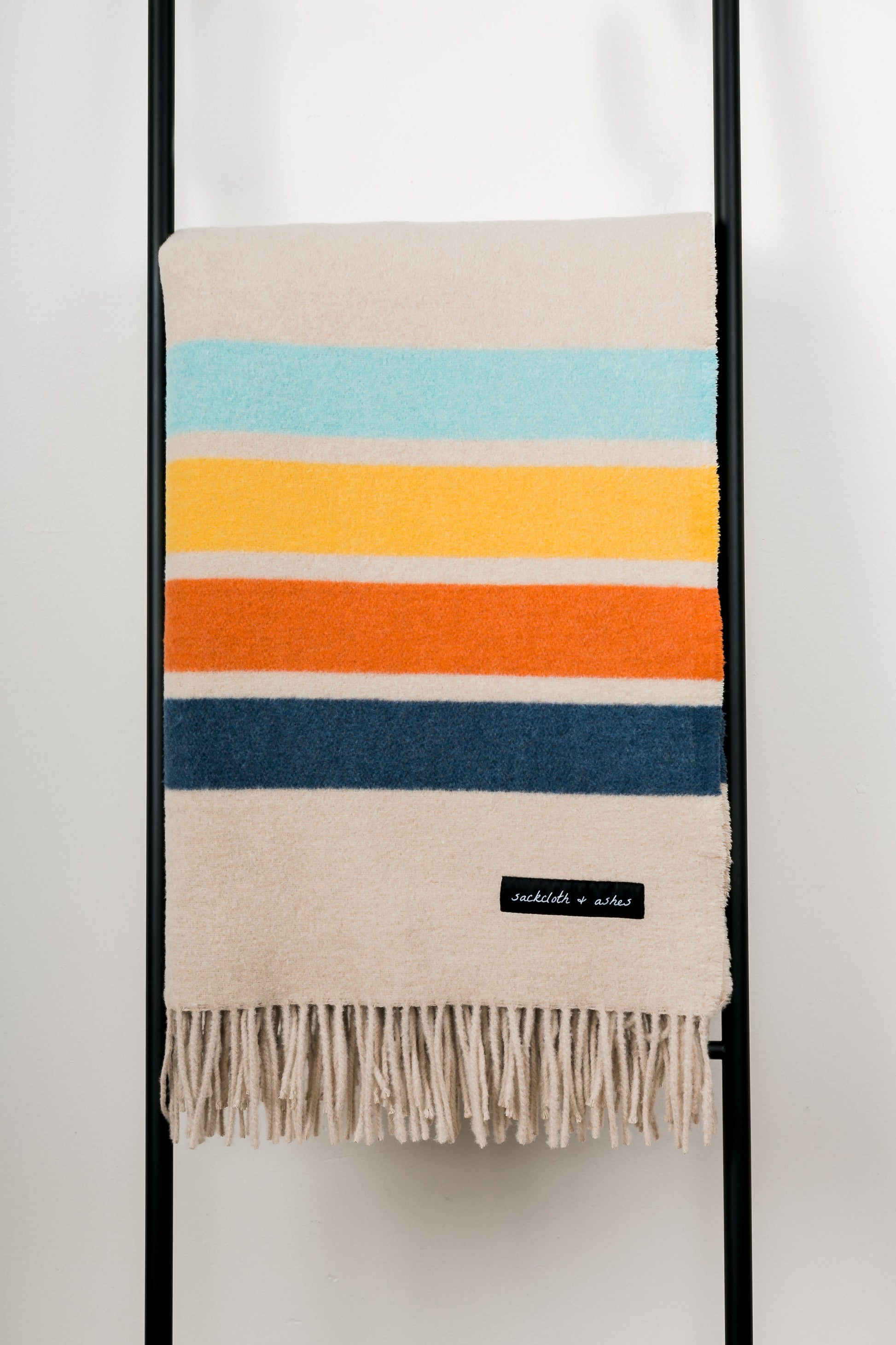 Striped blanket with colorful horizontal stripes on a black ladder against a white background