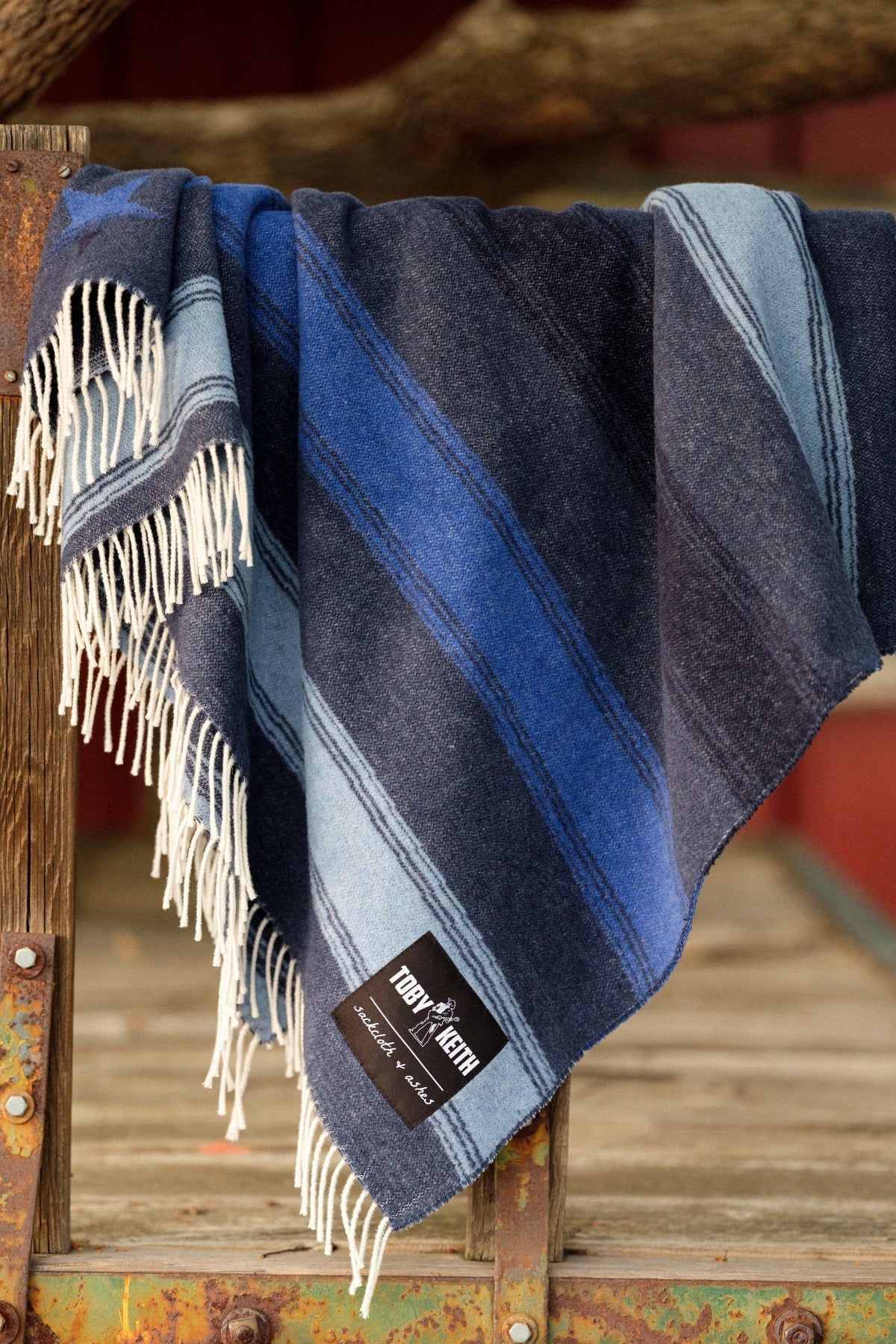 Blue plaid blanket with fringes draped over a wooden surface