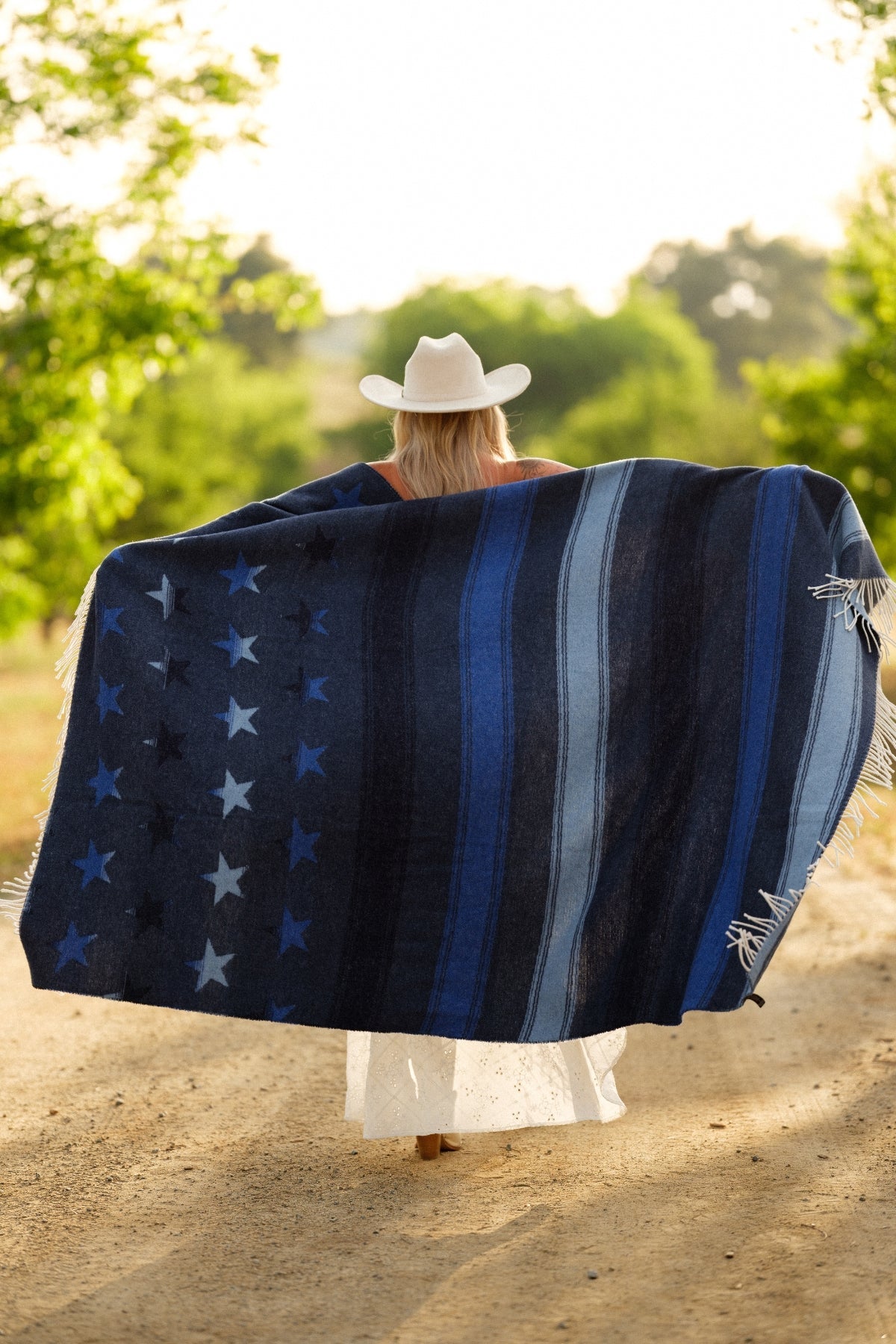 Person wearing a large blue and white patterned blanket outdoors