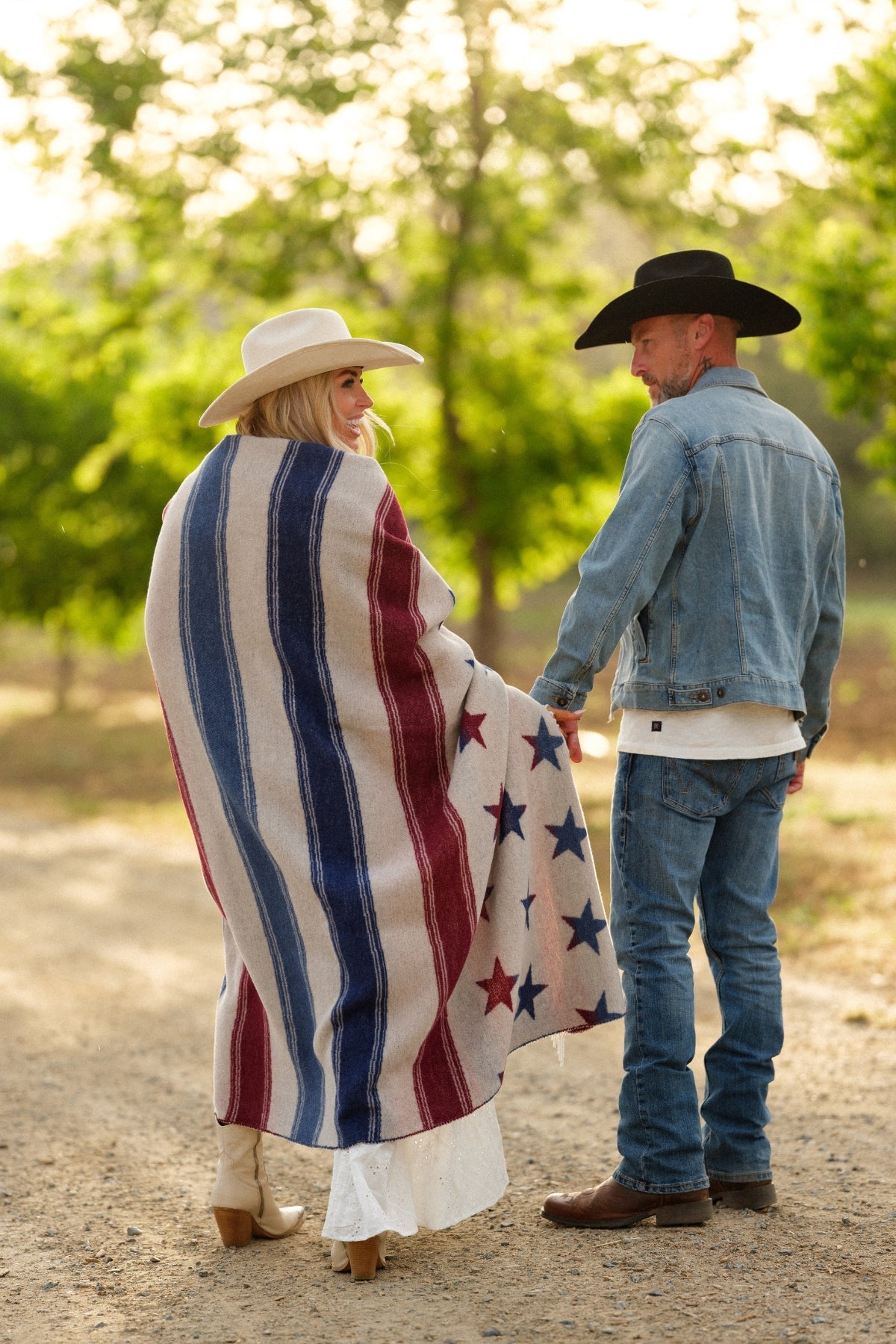 Two people standing outdoors with a person wrapped in a red, white, and blue striped blanket.
