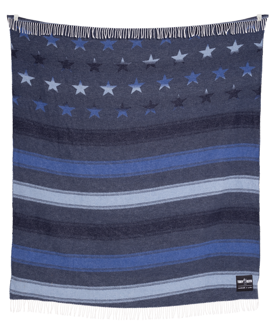 Navy blanket with star and stripe pattern, featuring a brand label on the corner.