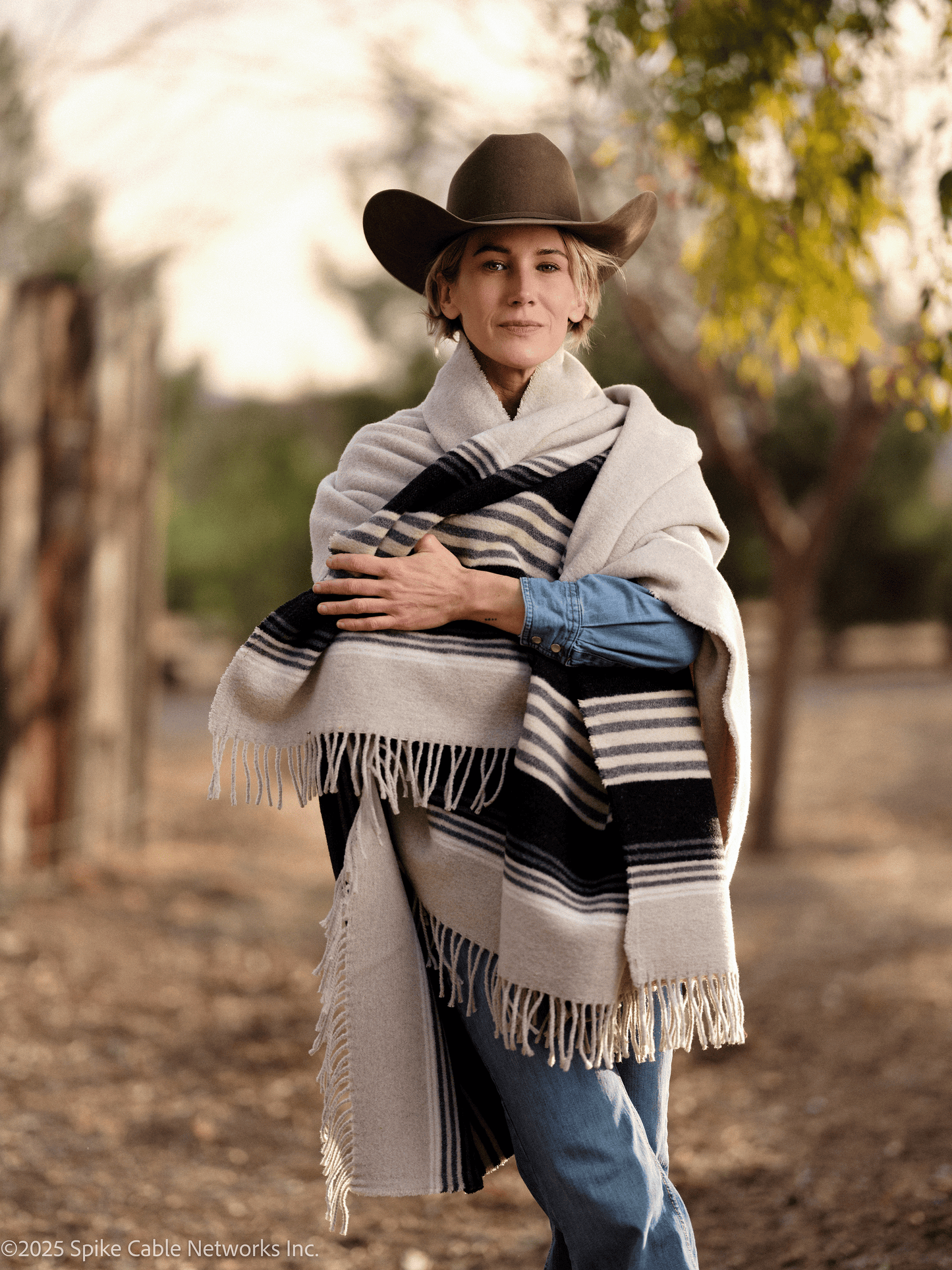 Woman wearing a cowboy hat and striped shawl in a natural setting