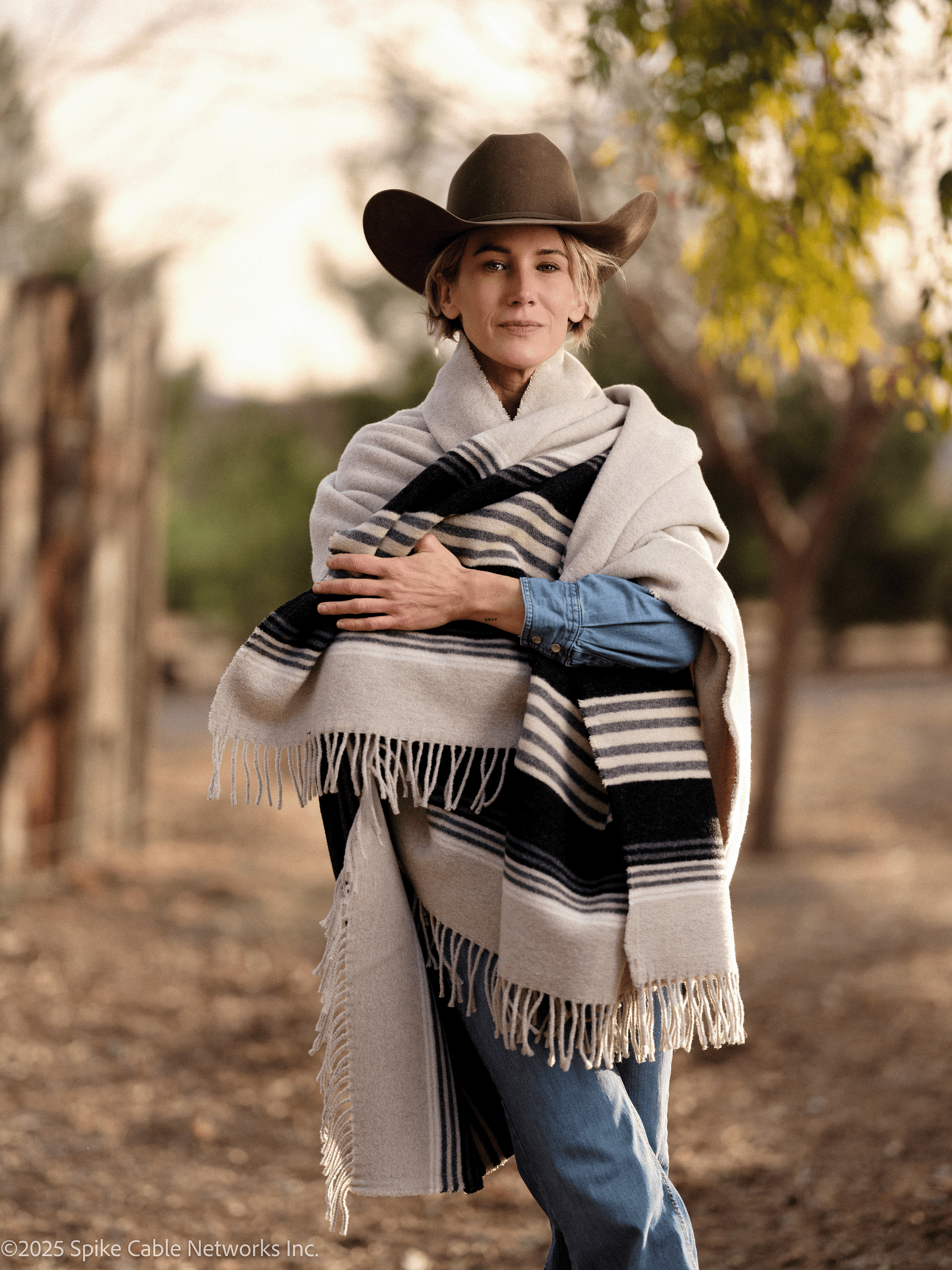 Woman wearing a cowboy hat and striped shawl in a natural setting