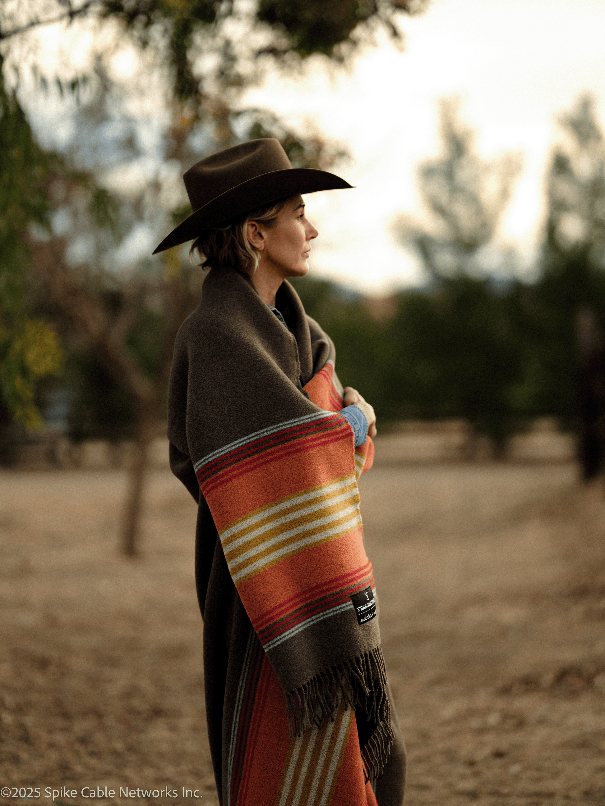 Person wearing a colorful patterned shawl and hat in a natural setting