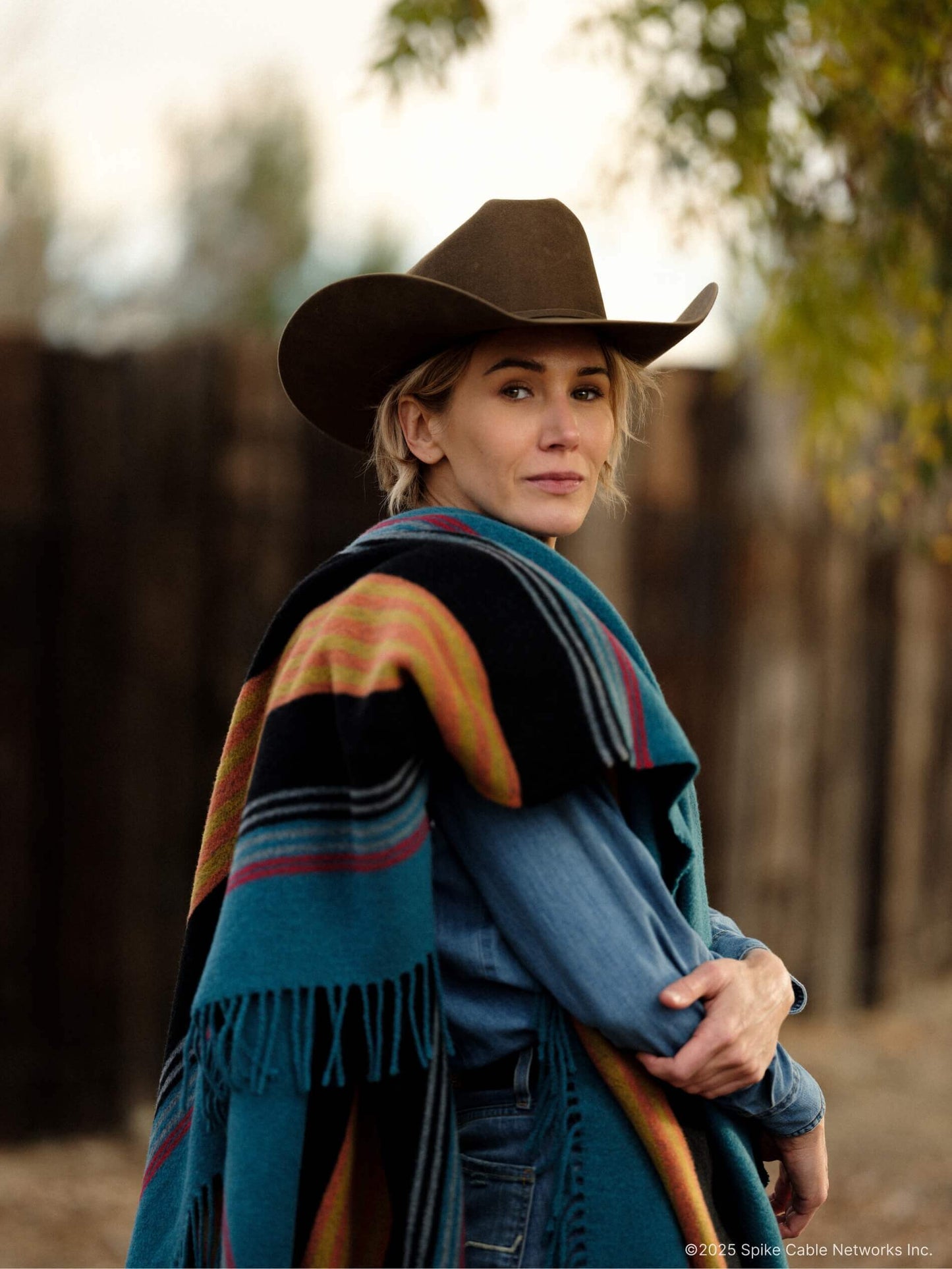 Person wearing a cowboy hat and colorful poncho in an outdoor setting