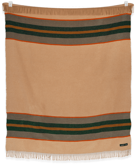 Beige blanket with horizontal stripes in green, brown, and orange on a black background