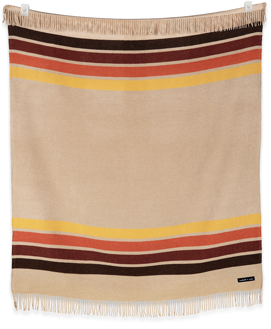 Beige blanket with multicolored stripes and fringes on a plain background