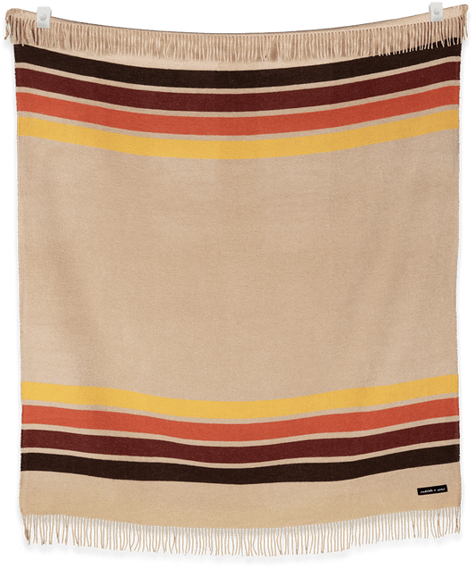 Beige blanket with multicolored stripes and fringes on a plain background