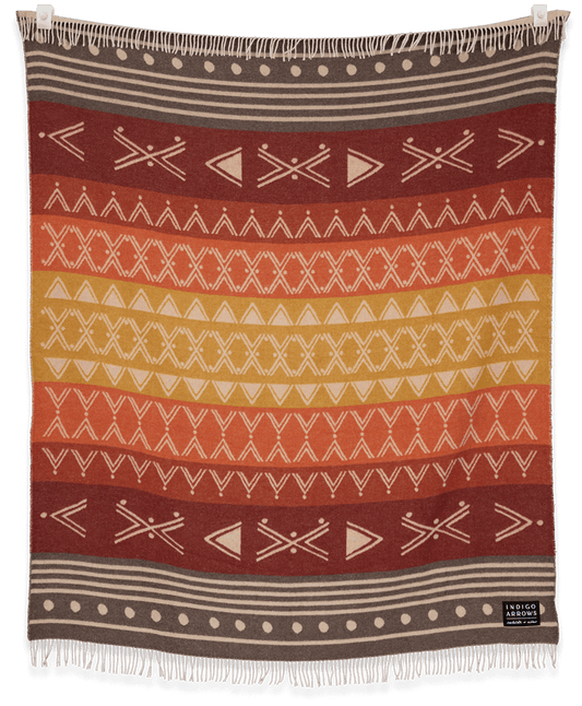 Woven blanket with geometric pattern in red, orange, and brown on a black background