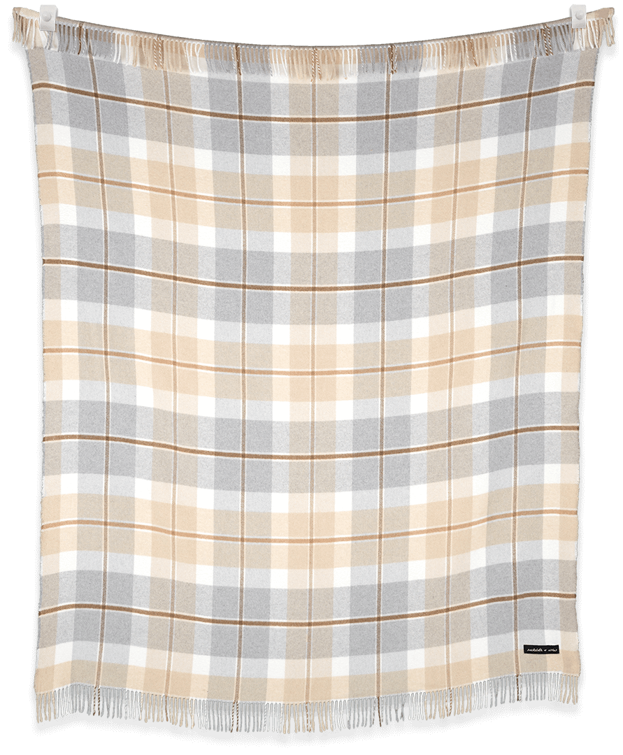 Plaid blanket with beige, gray, and white pattern on a black background