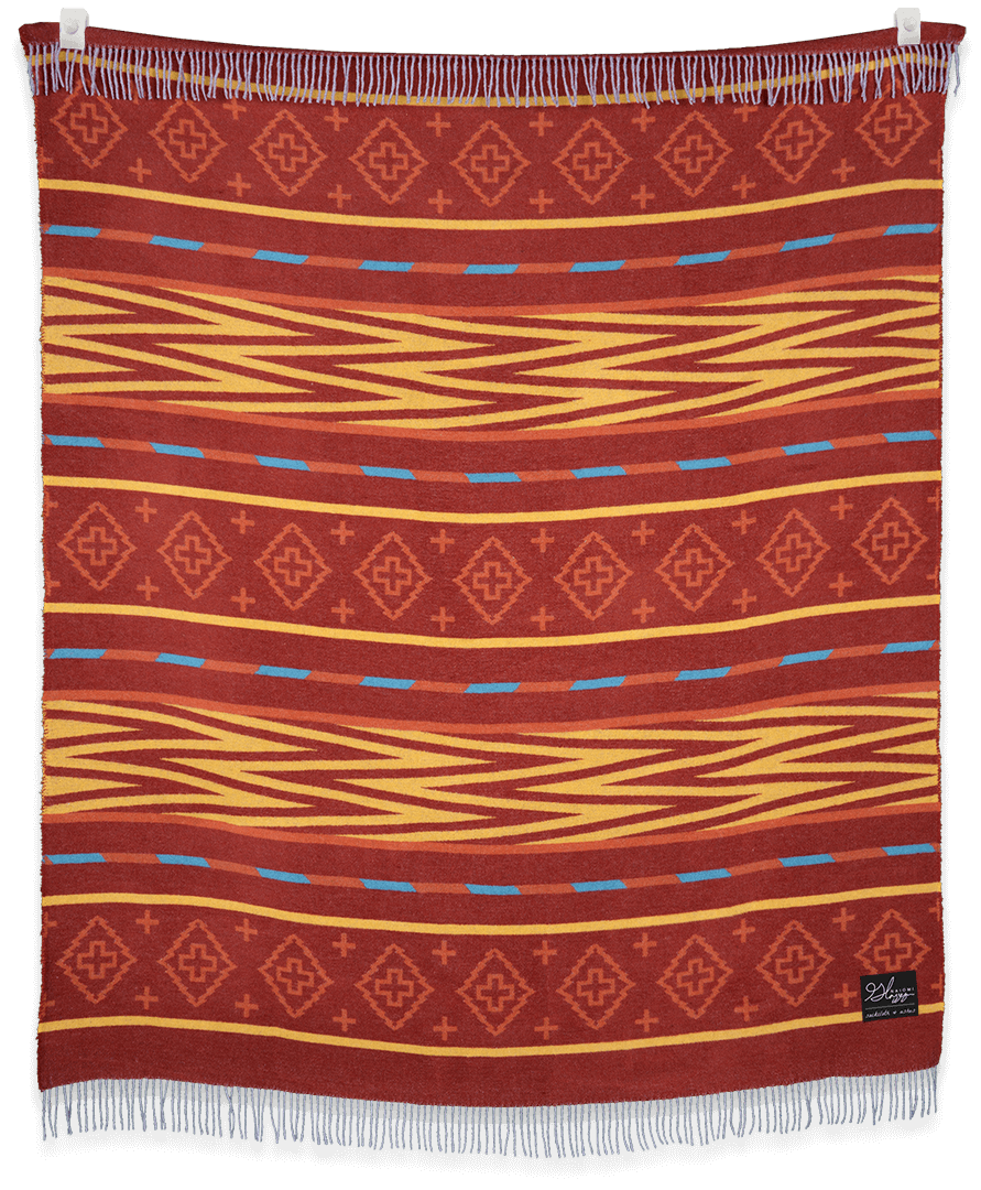Woven blanket with red, orange, and blue pattern on a black background