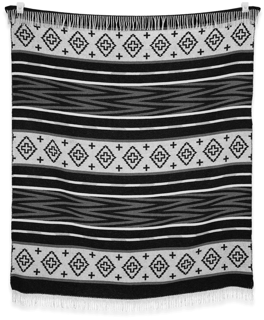 Black and white patterned blanket with fringes on a plain background