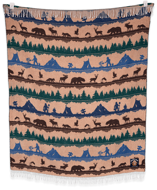 Woven blanket with nature-themed design featuring animals, trees, and mountains on a beige background.