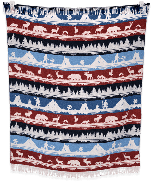 Woven blanket with nature-themed pattern featuring animals and landscapes.