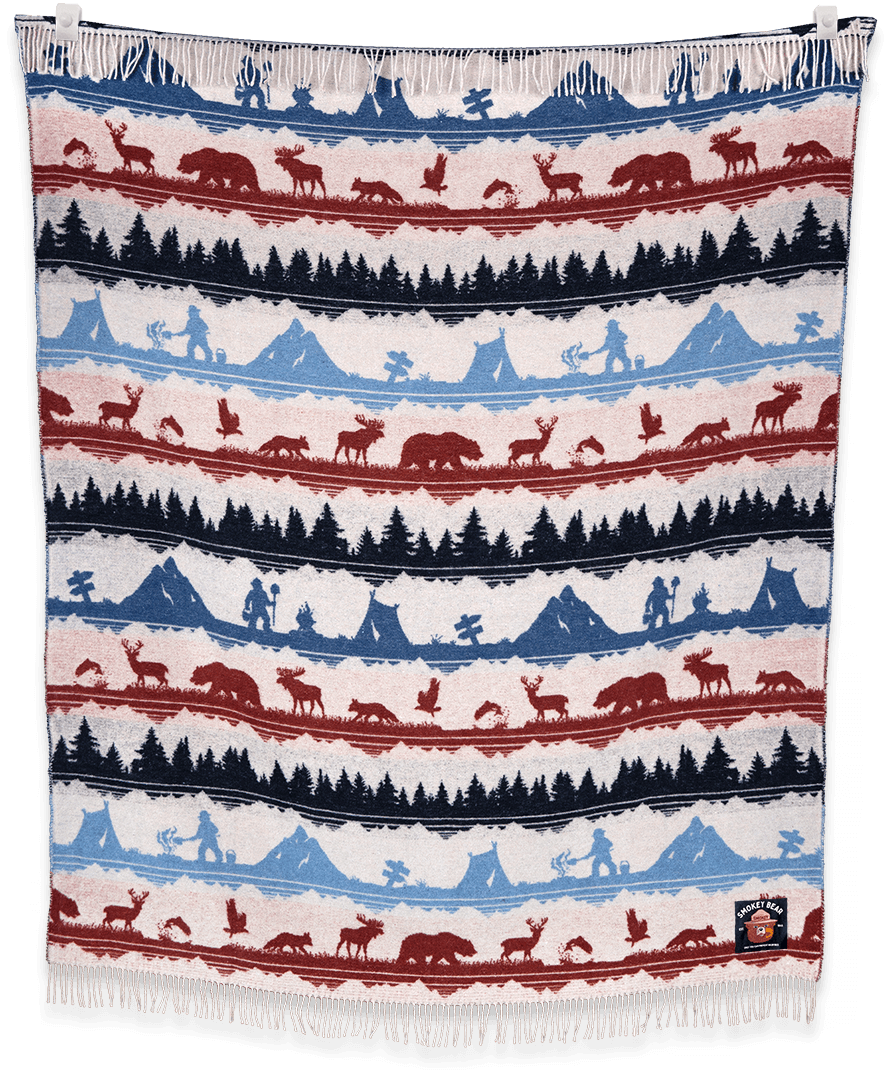 Woven blanket with nature-themed pattern featuring animals and landscapes.