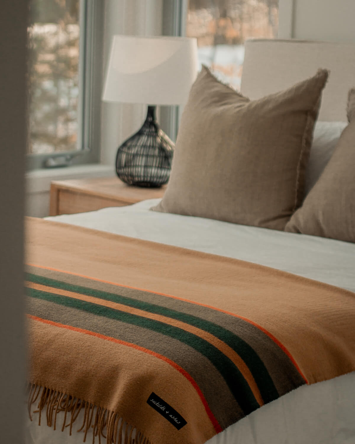 Bed with striped blanket and brown pillows in a bedroom setting