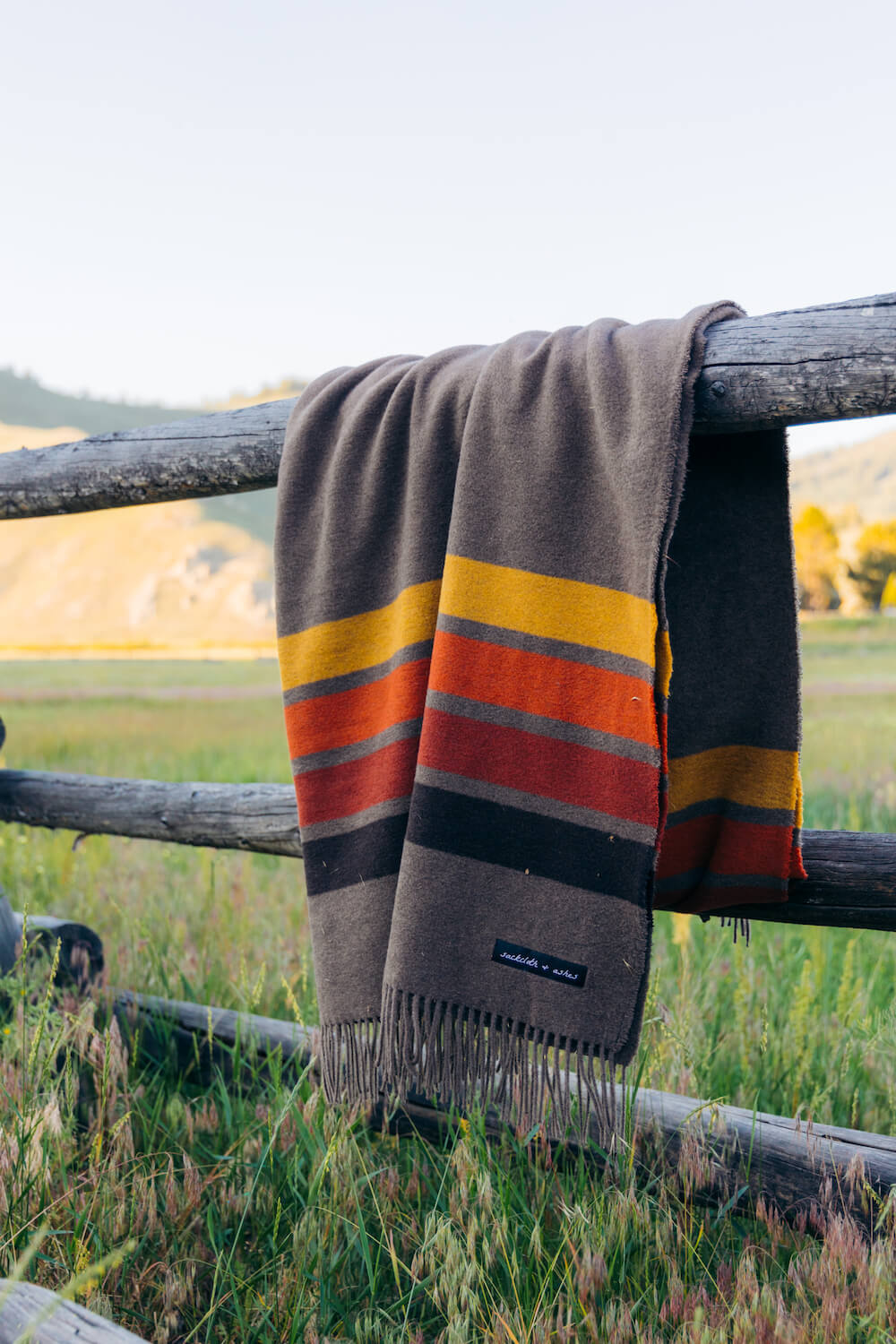 Striped blanket draped over a wooden fence in a scenic outdoor setting