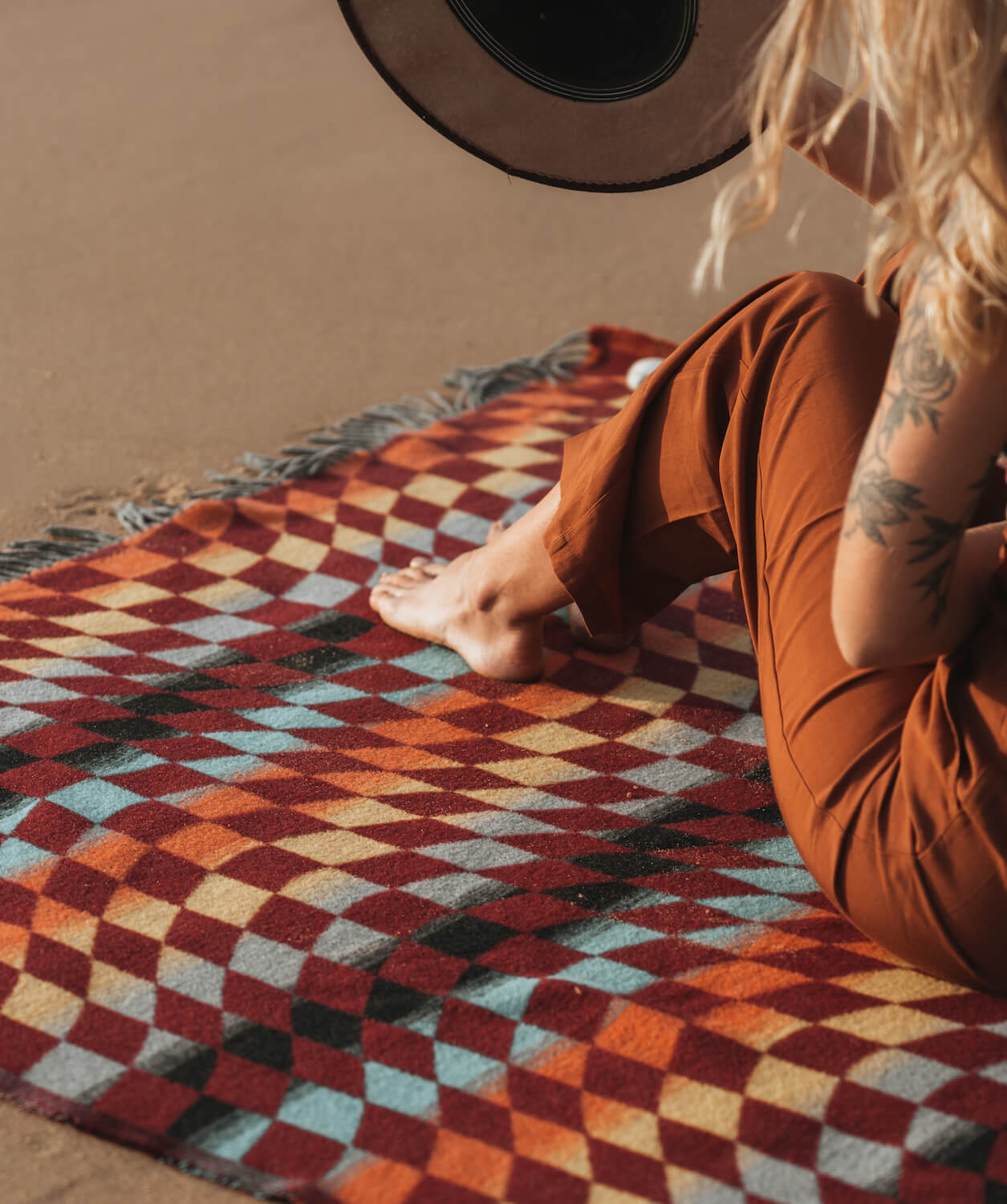 Person sitting on a colorful geometric-patterned rug with a guitar in the background