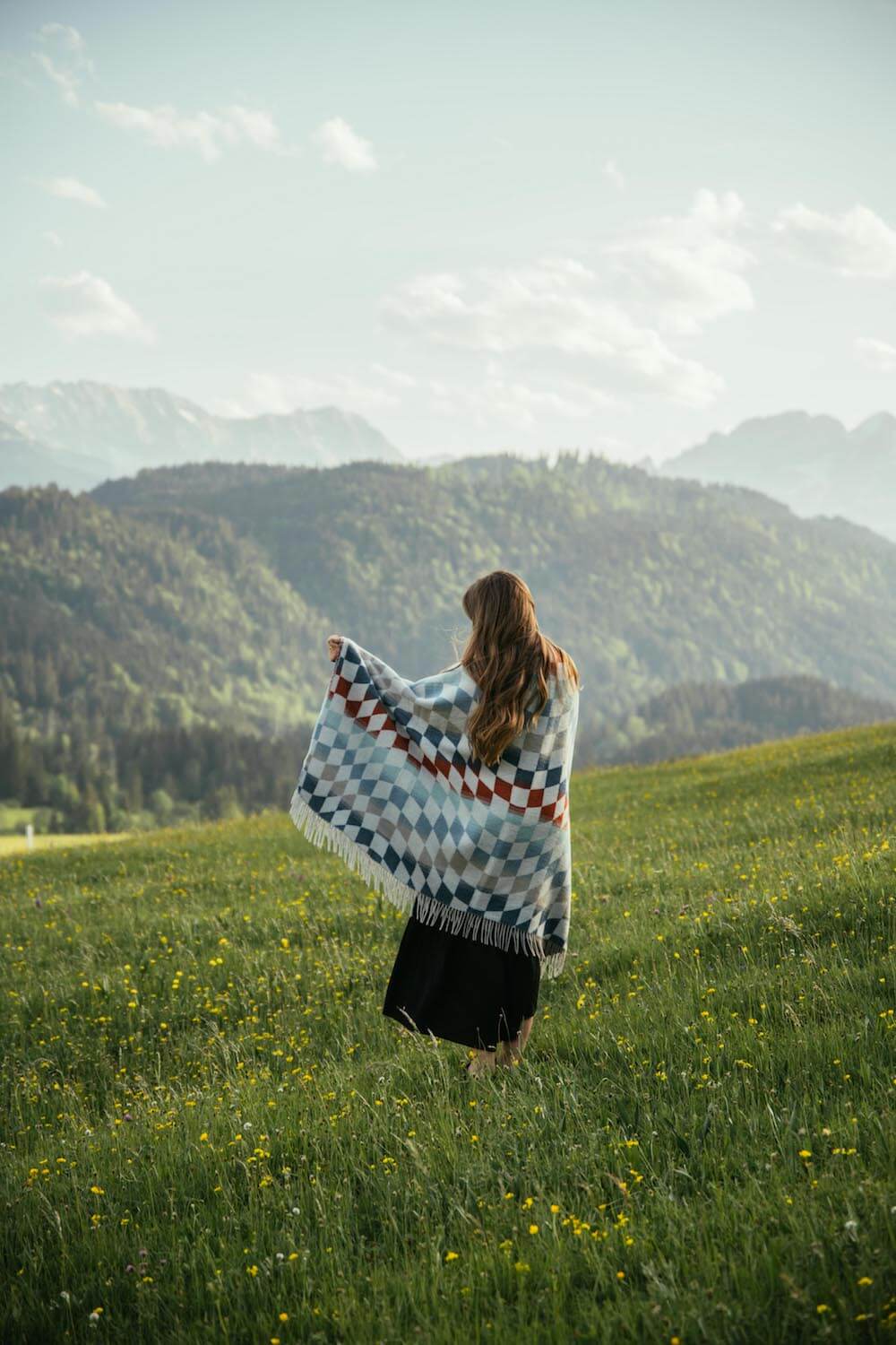 Person standing in a field with mountains in the background