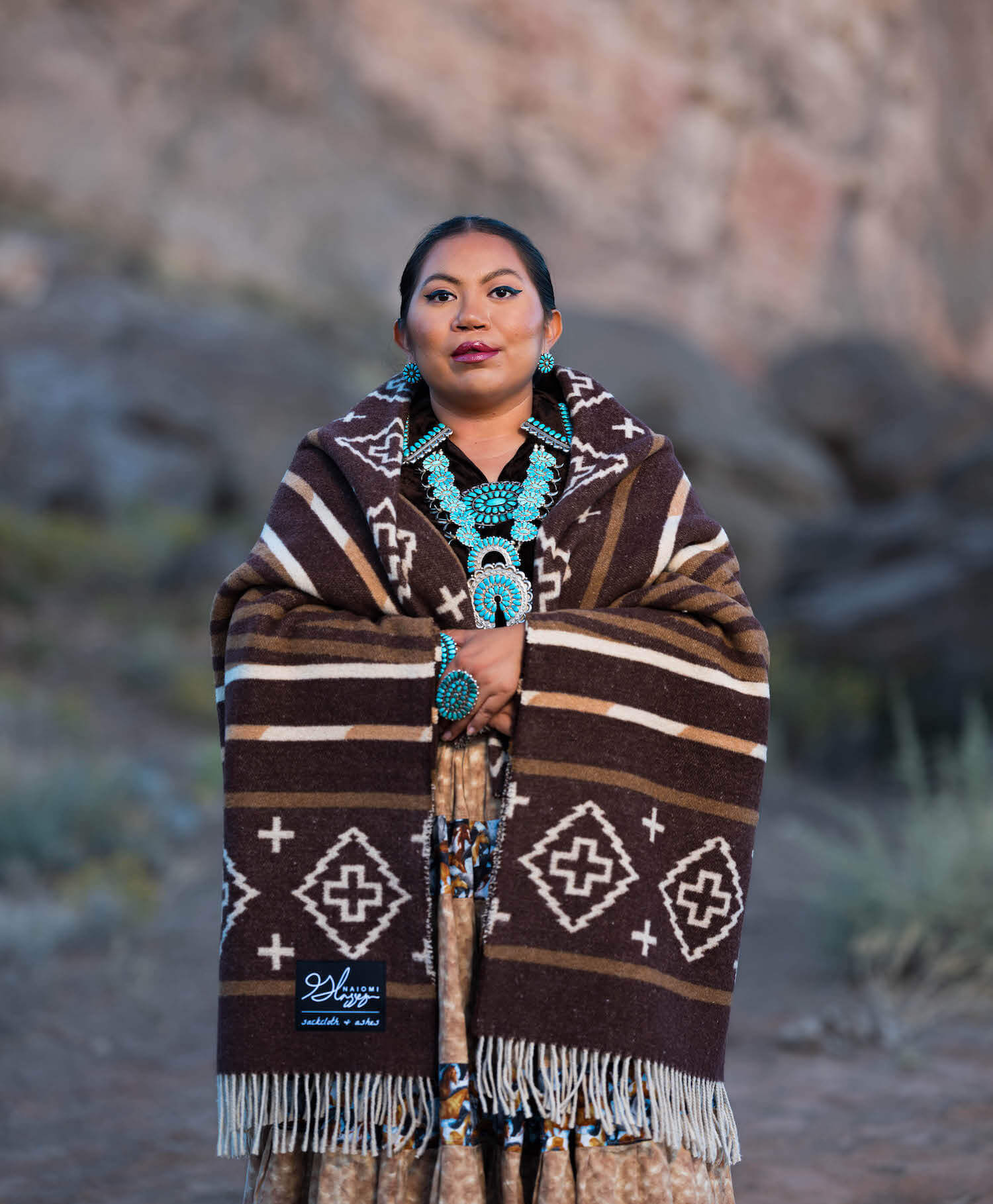 Woman wearing a patterned shawl with a desert landscape background