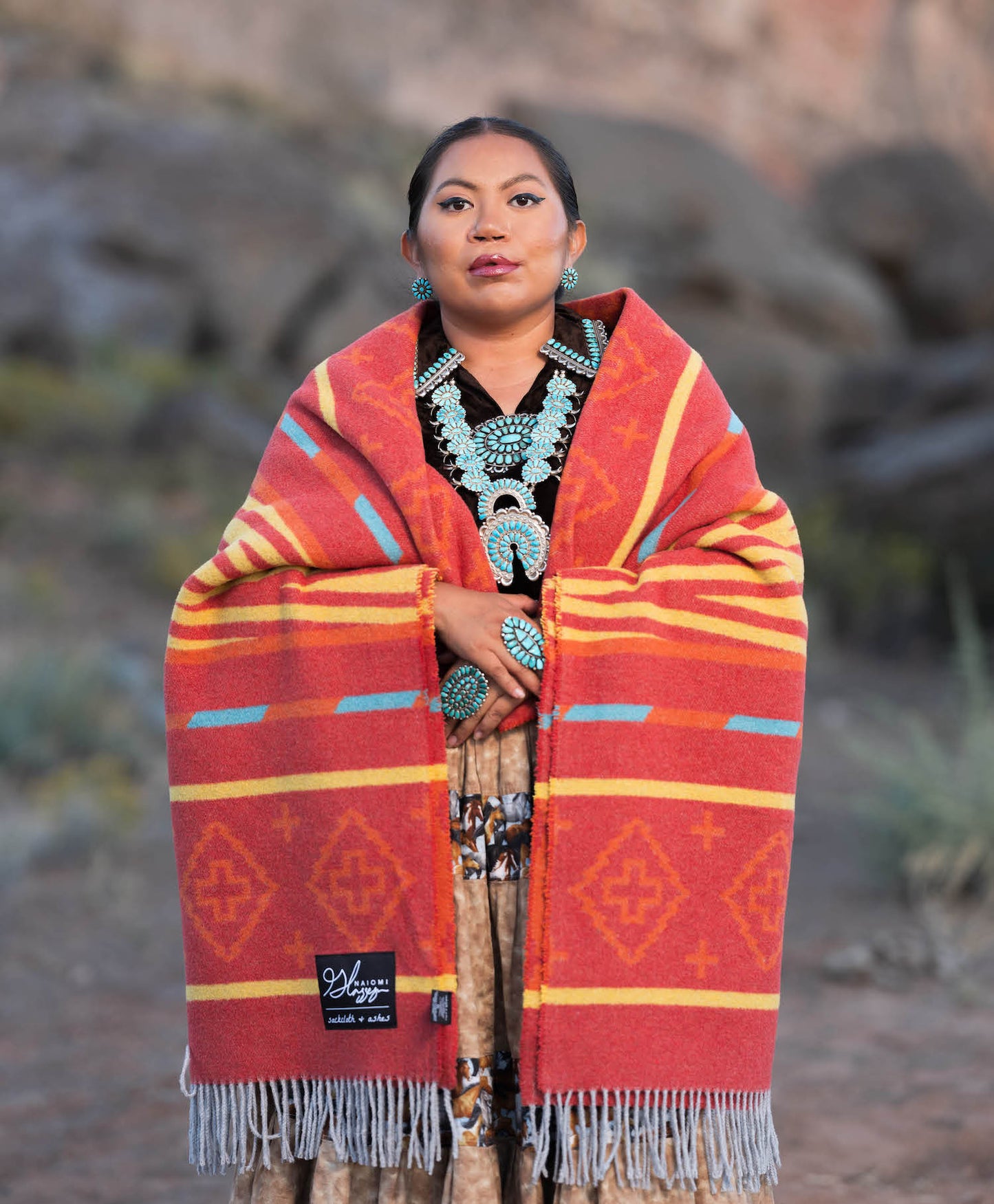 Person wearing a red patterned blanket with a blurred natural background
