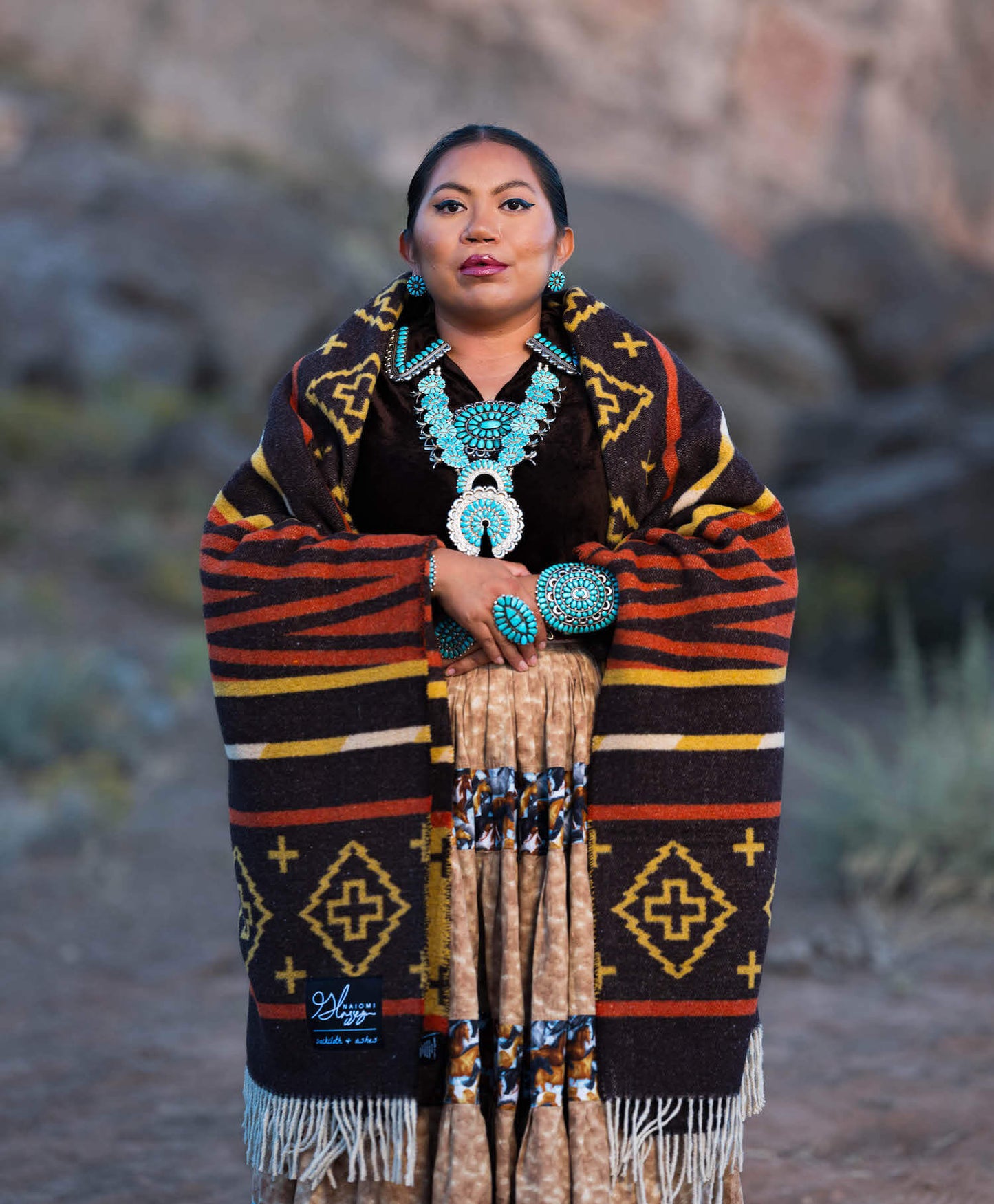 Woman wearing a patterned shawl and turquoise jewelry in a desert setting