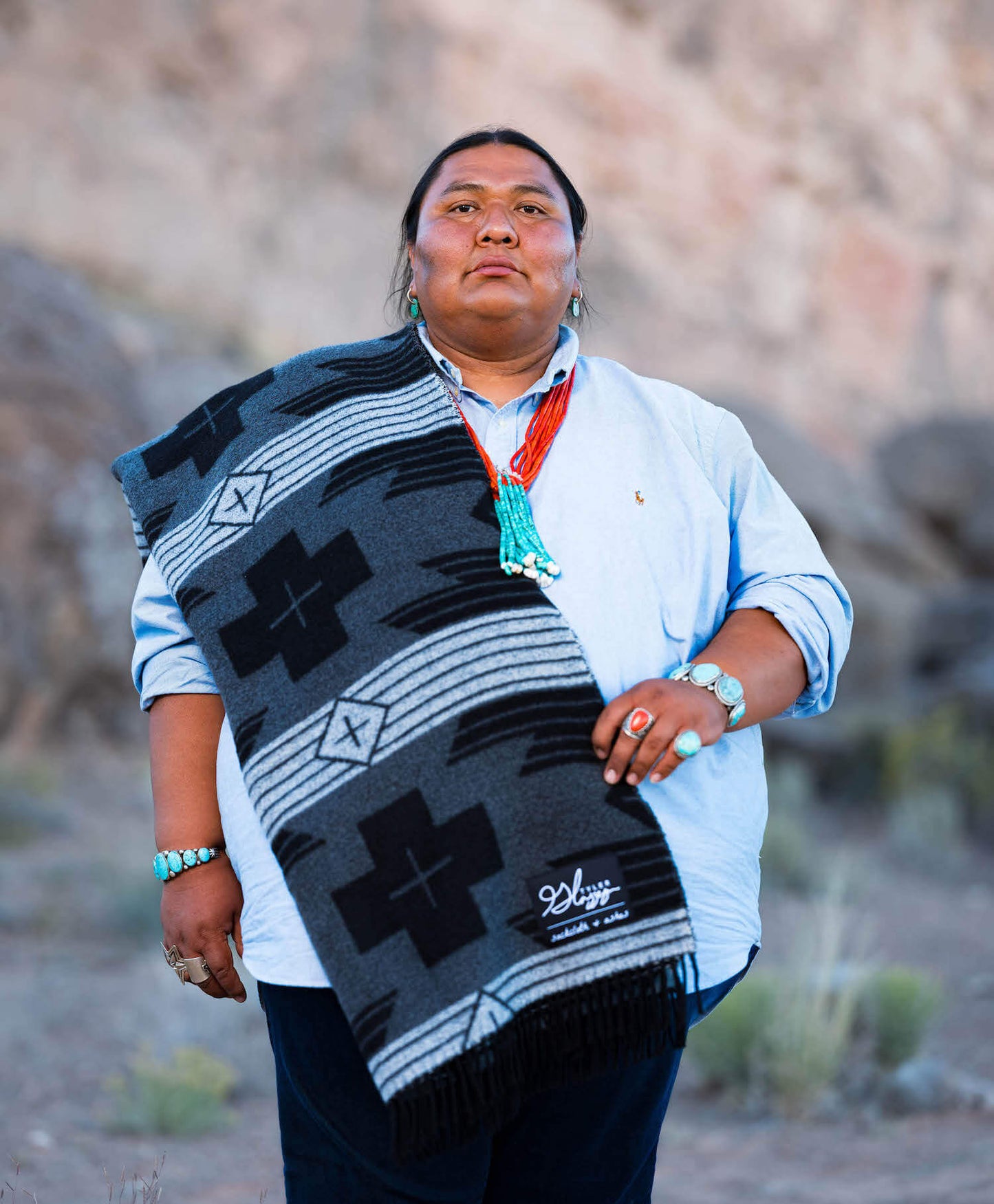 Person wearing a patterned blanket over shoulders in a desert setting