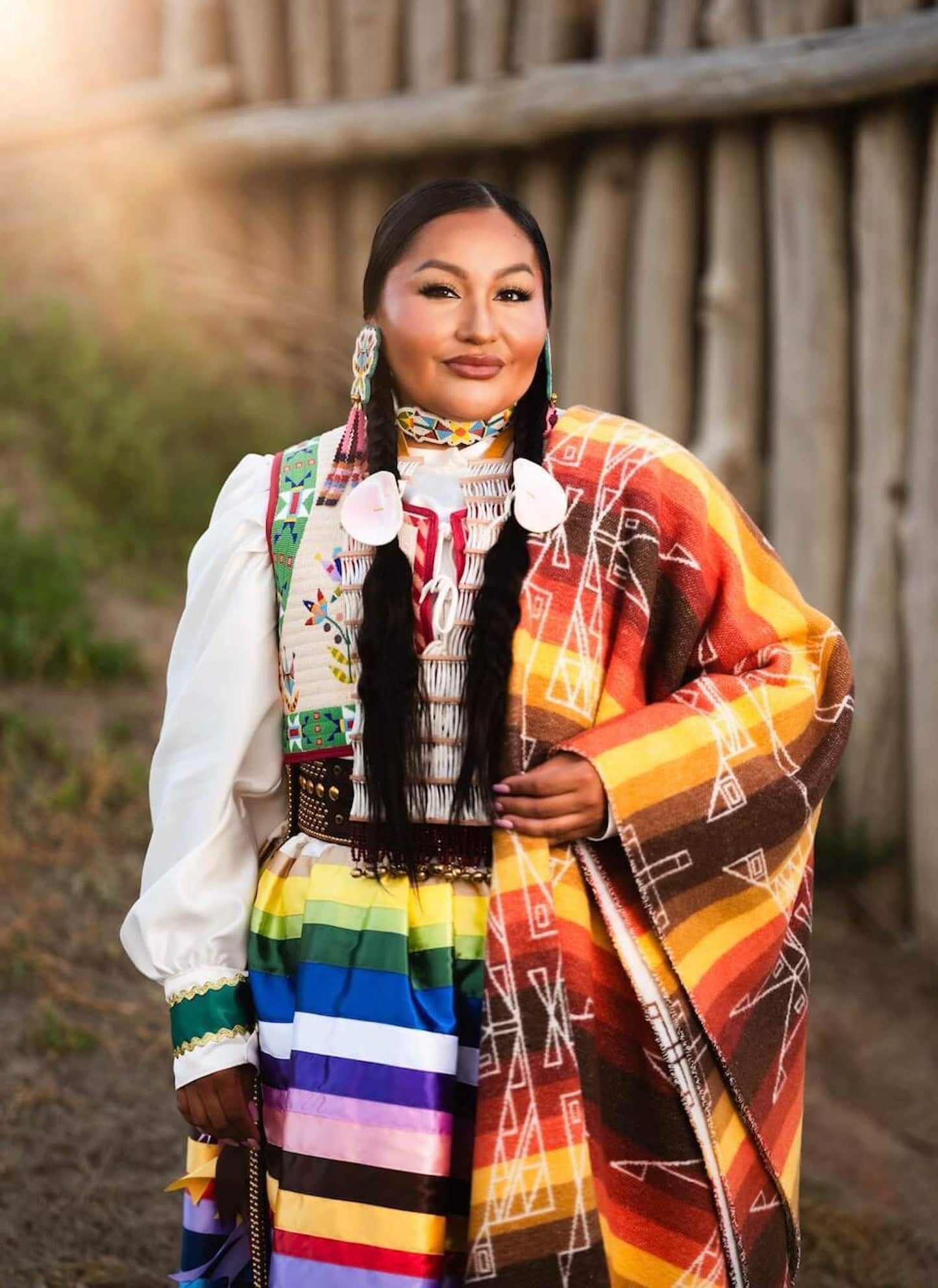 Person wearing a traditional multicolored outfit with a patterned shawl outdoors.