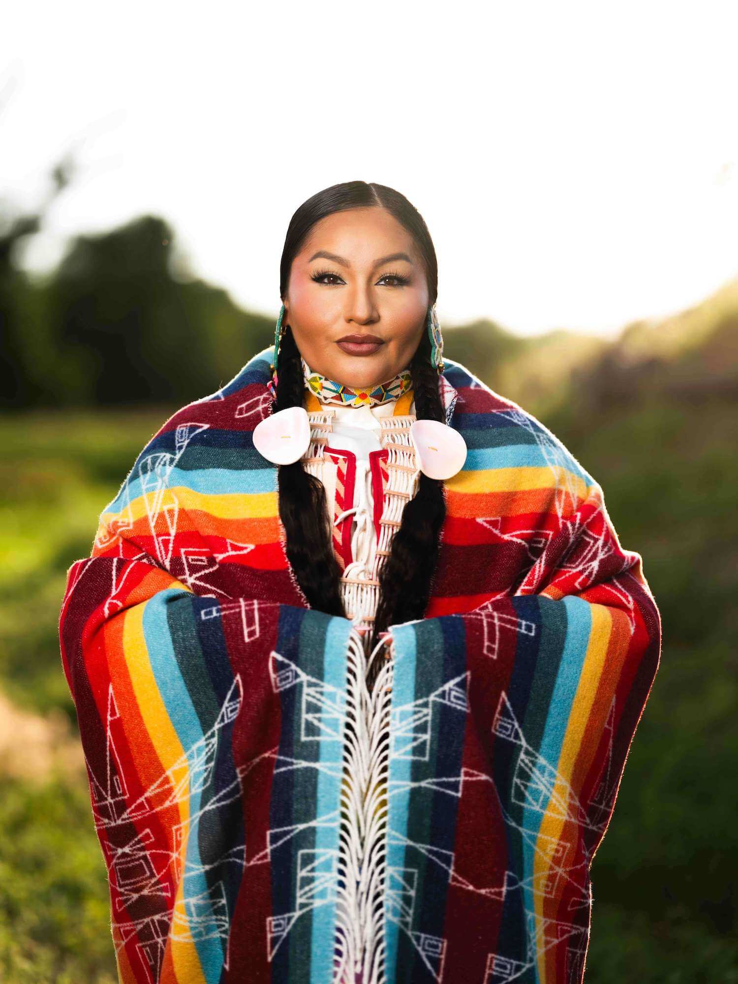 Person wearing a colorful traditional garment with a blurred natural background
