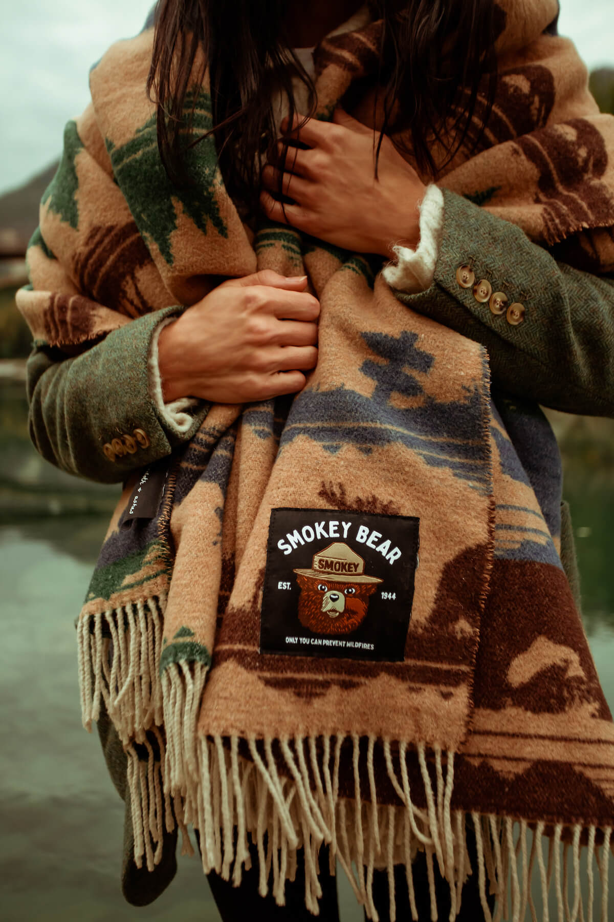 Person wearing a patterned scarf with a Smokey Bear patch, standing outdoors.