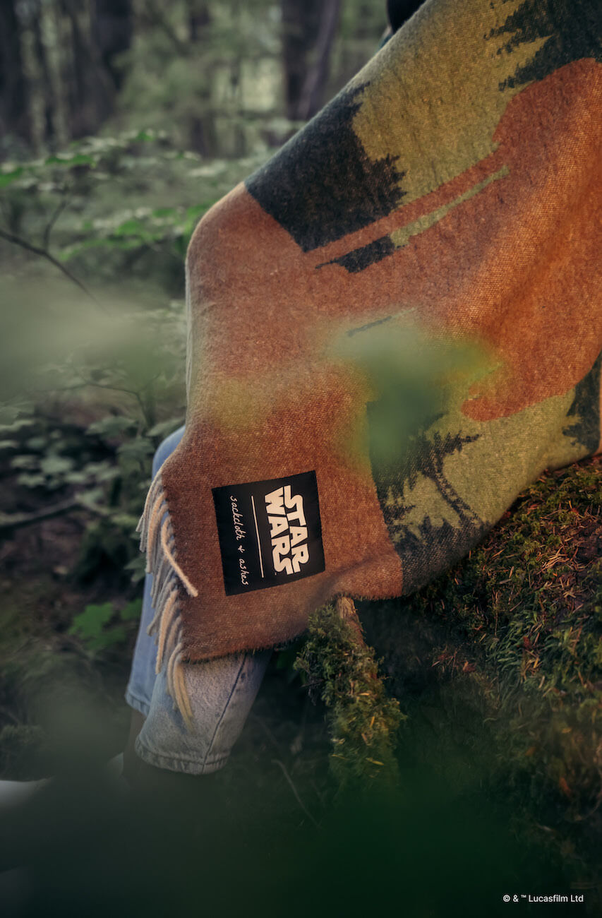 Person wearing a camouflage-patterned jacket with a visible brand logo in a forest setting