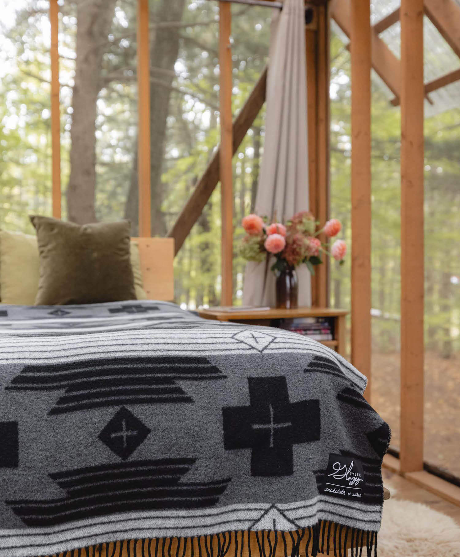 Gray patterned blanket draped over a chair with a forest view in the background