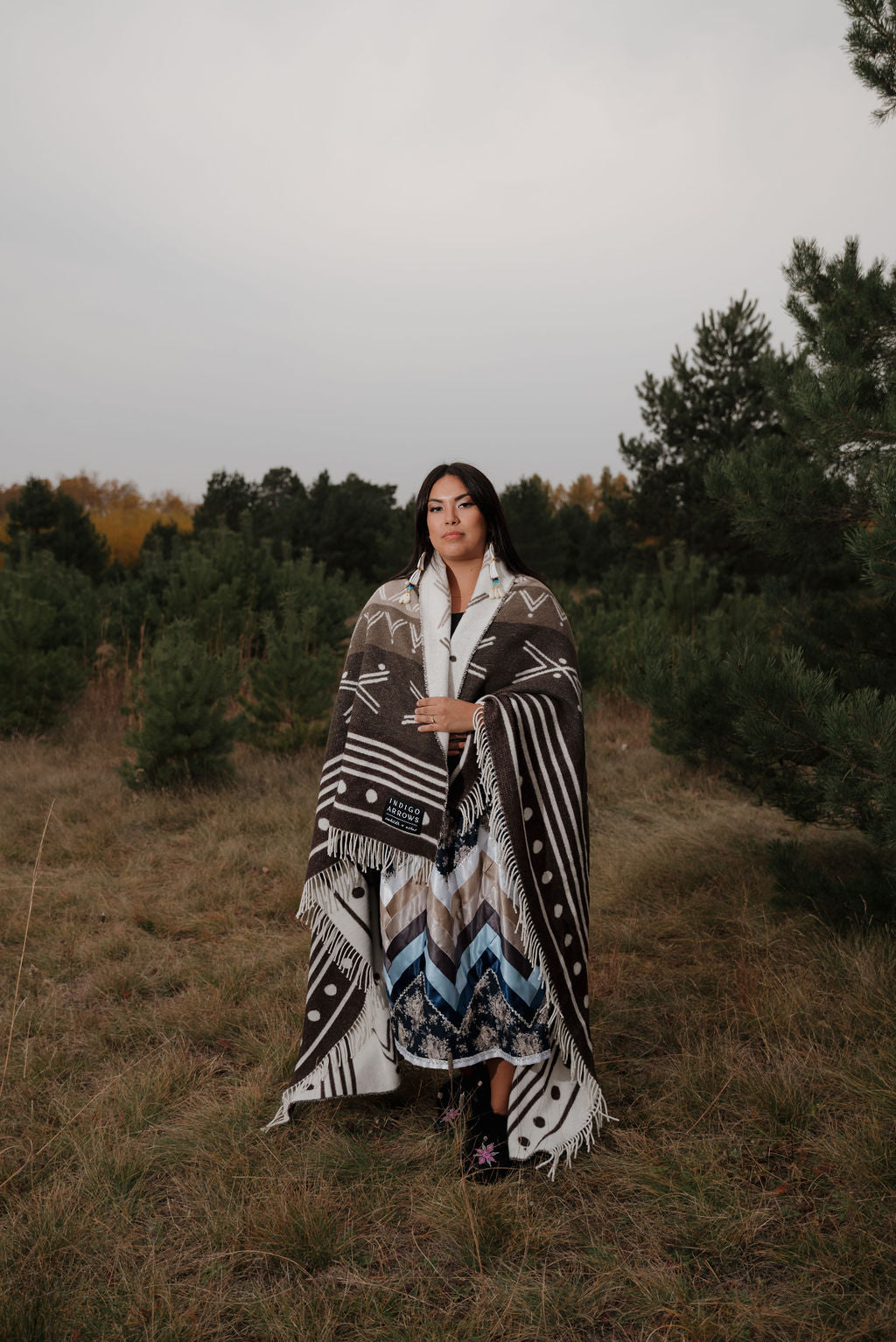 Woman wrapped in a patterned blanket standing in a forest