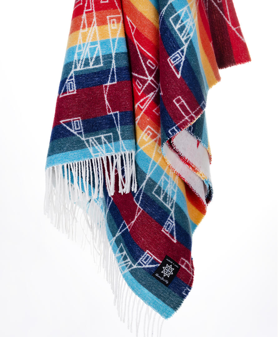 Colorful patterned blanket with fringes on a white background