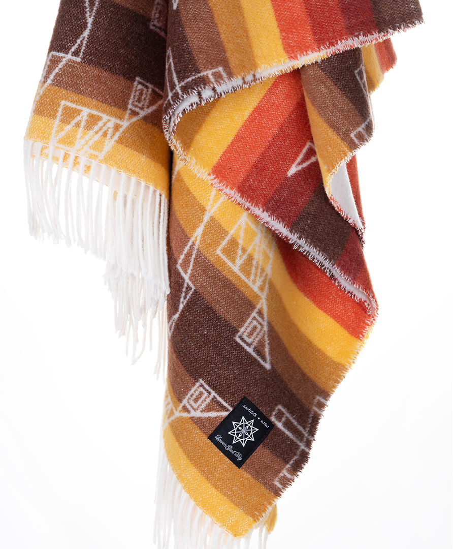 Patterned blanket with fringes and a logo on a white background