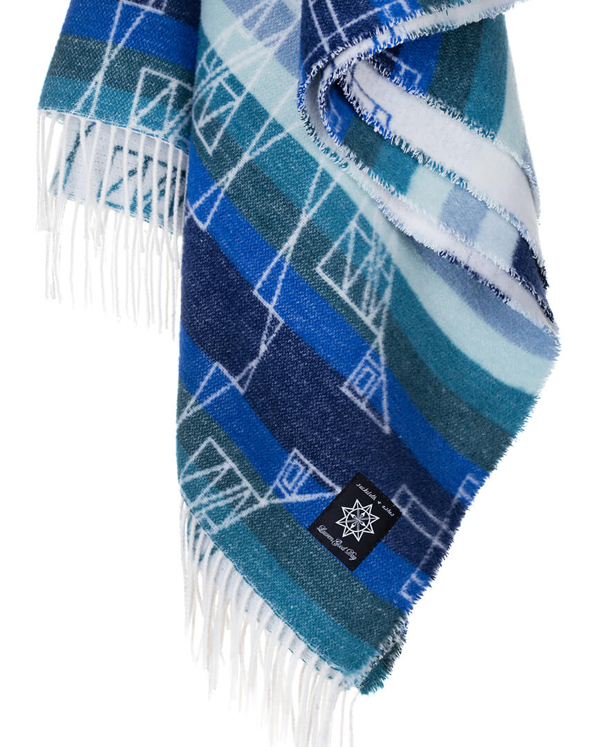 Blue plaid scarf with white geometric patterns and fringes on a white background