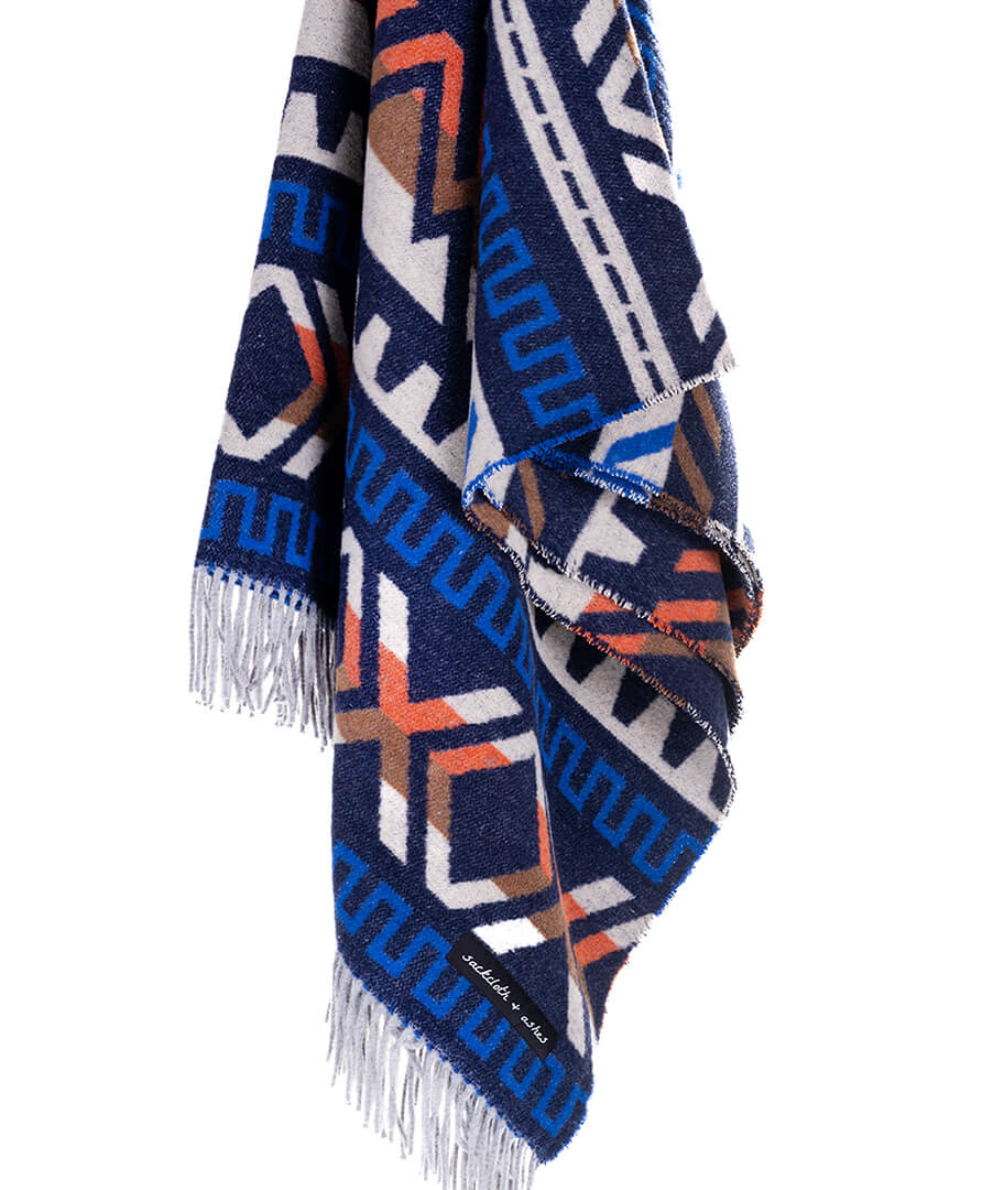 Navy blue patterned blanket with white, orange, and brown accents on a white background