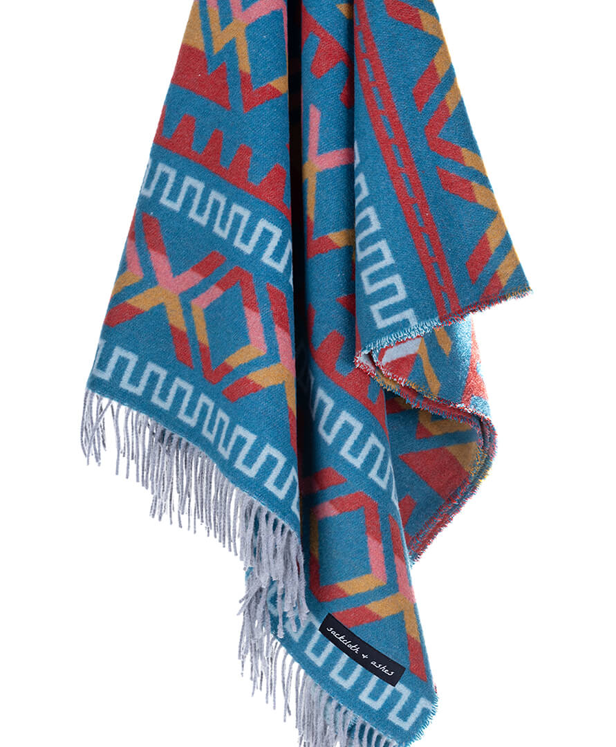 Folded blanket with geometric pattern and fringes on a white background
