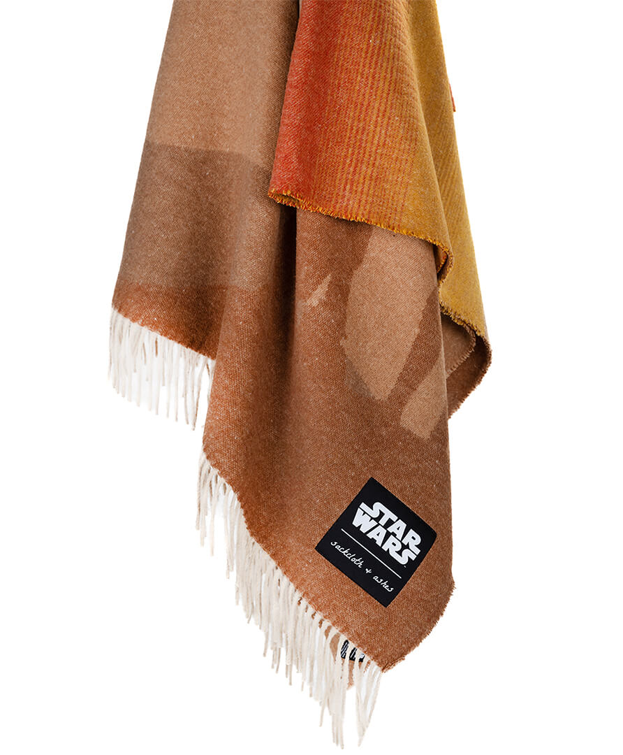 Brown and orange plaid blanket with fringes and a 'Star Wars' logo on a white background