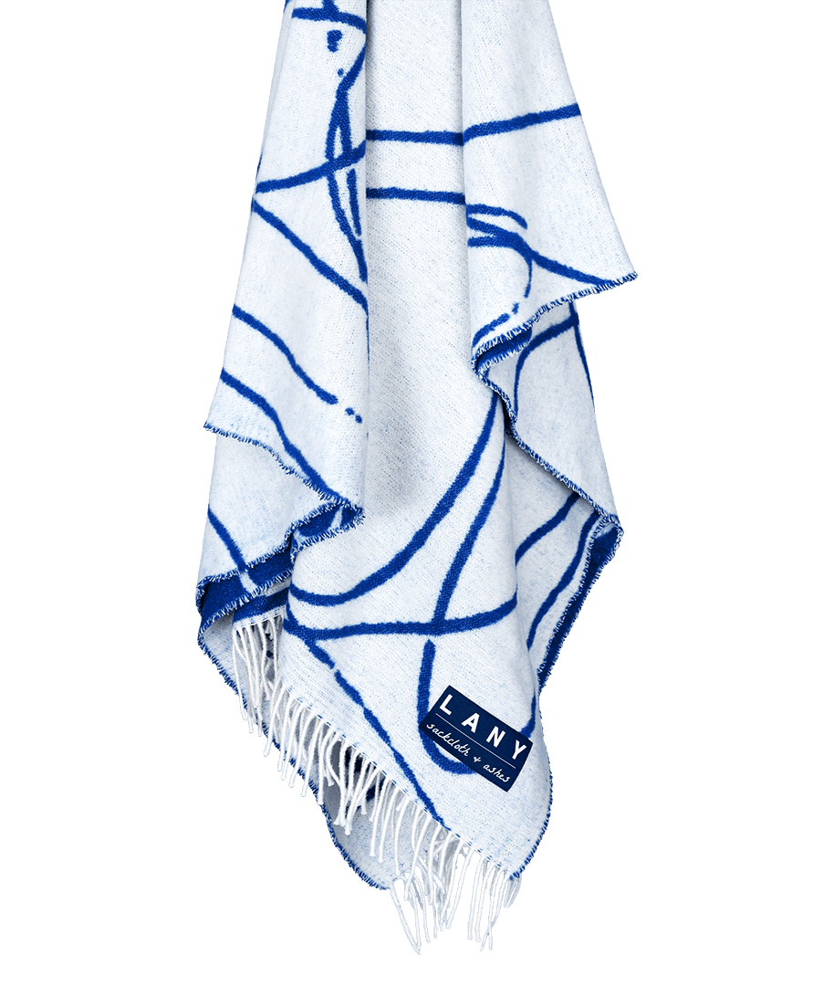 White towel with blue abstract patterns and fringes, featuring the brand 'LANY'.