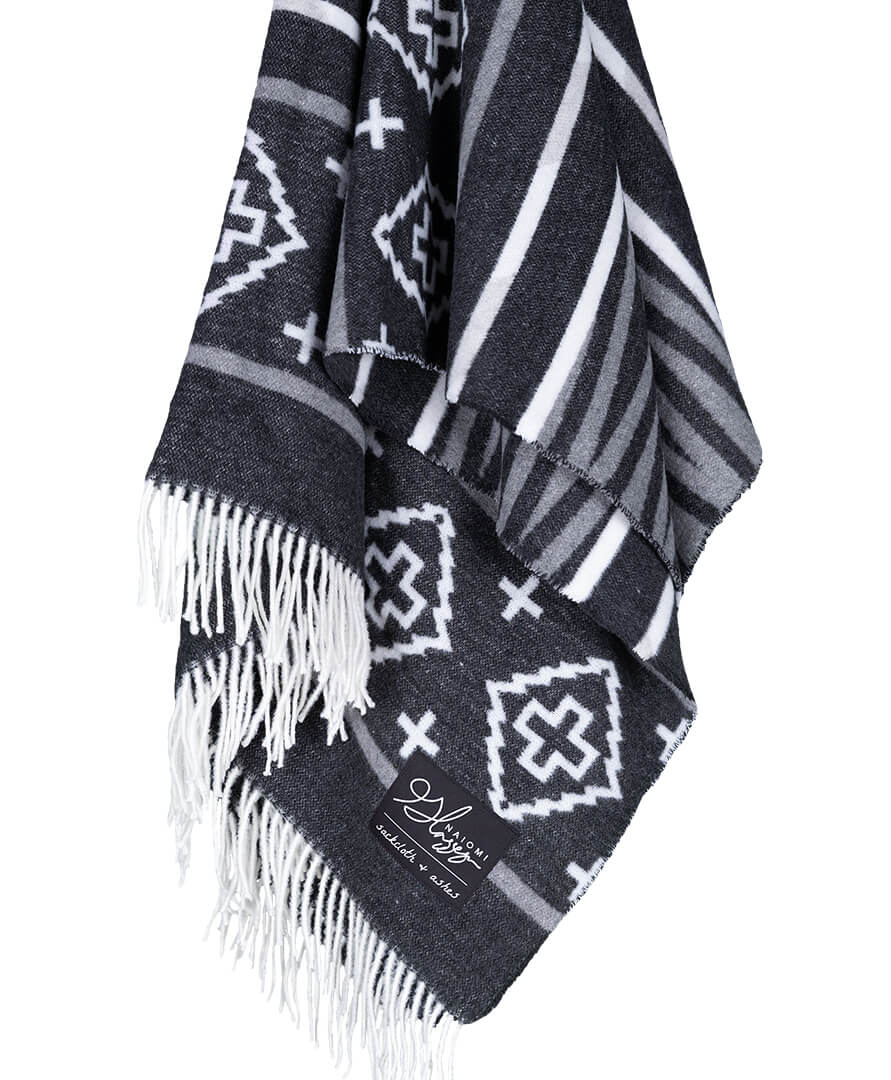 Black and white patterned blanket with fringes on a white background