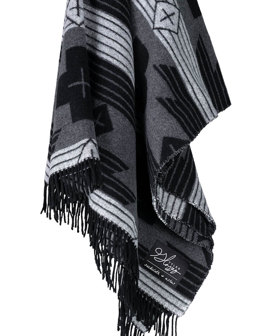 Black and gray patterned blanket with fringes on a white background