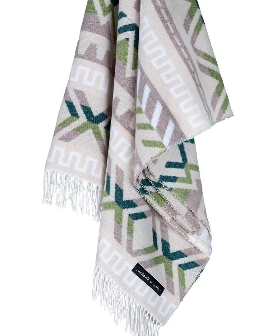 Geometric patterned throw blanket with fringes on a white background