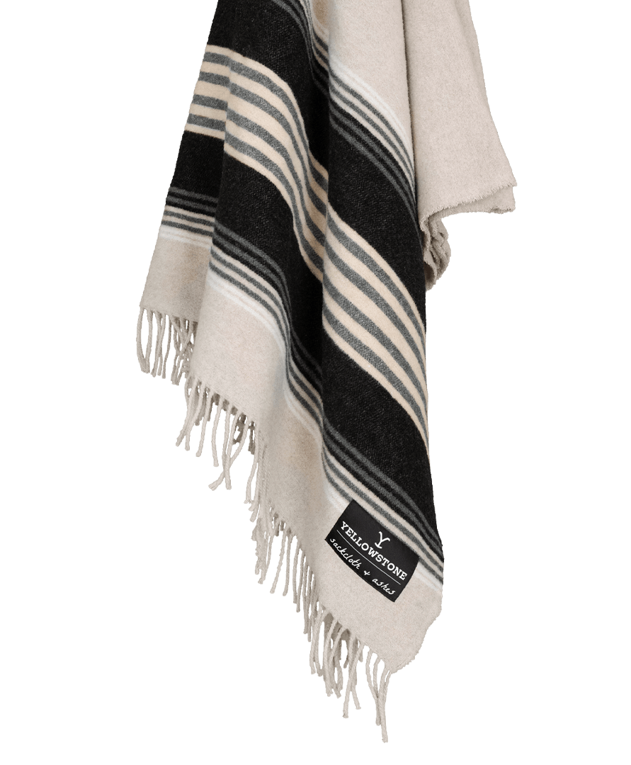 Striped black, white, and gray blanket with fringes on a black background